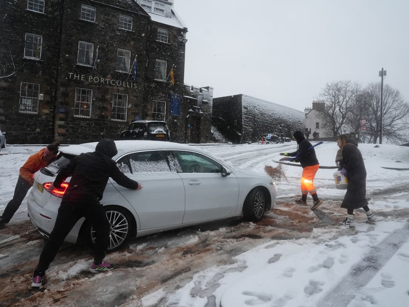 People help a driver struggling in the snow in Stirling PIC: Andrew Milligan/PA Wire