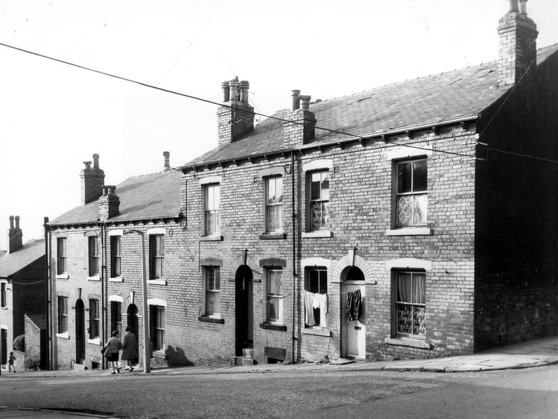 Two women walk down Silver Royd Grove while clothes hang on a line stretched across the front of number 2. Pictured in October 1968.