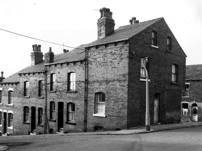 On the left of the image are three double fronted back-to-back terraced houses with a shared outside toilet yard on the left. On the right is the gable end entrance to number 8 Silver Royd Road with Silver Royd Grove visible on the far right.