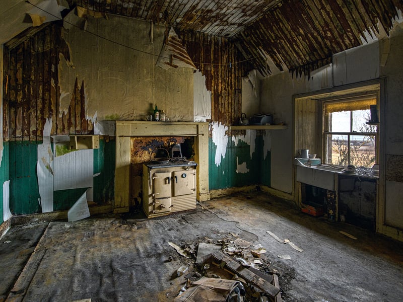 Once a fine kitchen at the heart of this house at Upper Borgue in Caithness, the stove now stands cold. Empty bottles sit on the fireplace. 