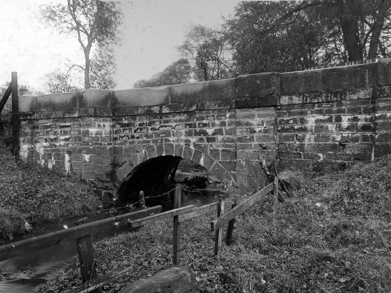 Bridge carrying Stairfoot Lane across Adel Beck. This is looking from the west, the City Engineers Department noted on this photograph that water can be seen behind the bridge face and approaches. The darker discolouration is visible on the stone-work. Pictured in October 1932.