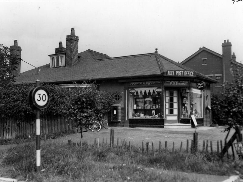 Adel Post Office at the junction of Otley Road and the Crescent, business of Fredrick Sidney Smith. Single storey building extension of adjoining bungalow. A post box is on the left wall. A road sign for 30 mile per hour speed limit is also to the left. Pictured in July 1936.