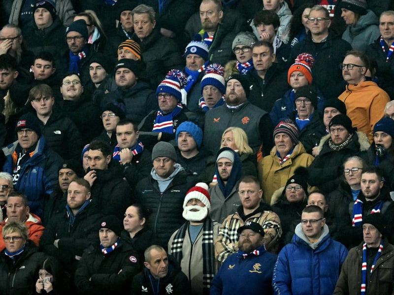 A fan wears a Santa hat with a beard in the Ibrox home end.