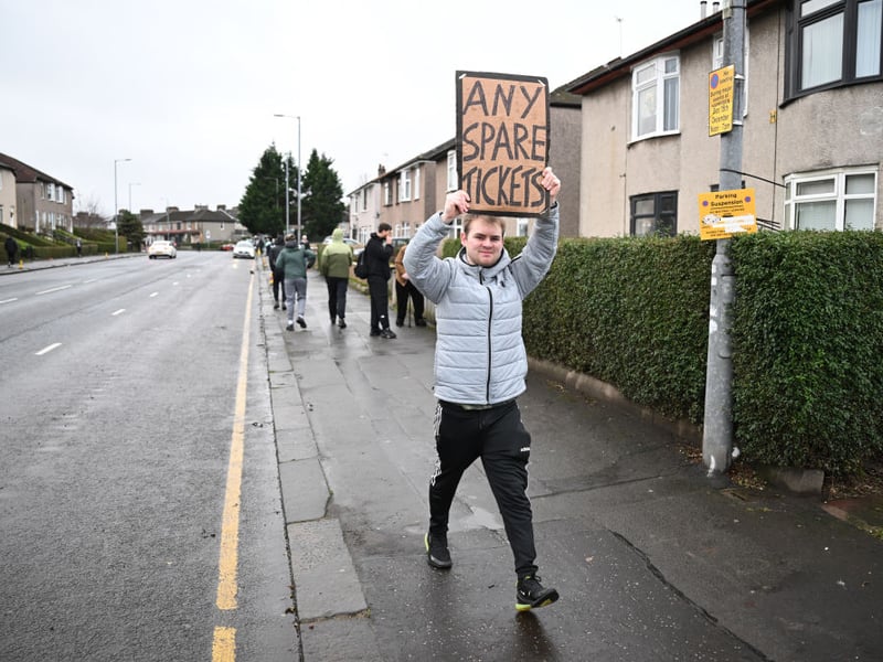 A person walks outside the stadium with a banner reading 'any spare tickets' prior to the Premier Sports Cup Final.