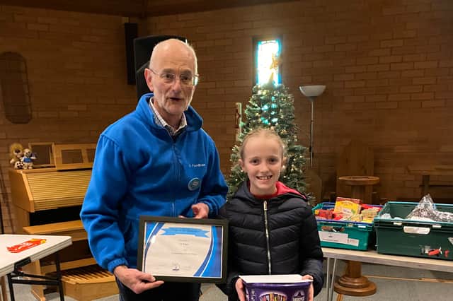 Lily receives a certificate of appreciation from John Hull after raising £1,200 for the S2 Food Bank