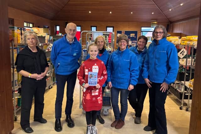 Lily meets the S2 Food Bank volunteer team after raising £1,200. She is holding the book which inspired her fundraising mission.