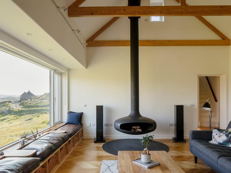 The house has been designed to maximise the views across the sands. At one end of the house, a log burner is suspended above a Caithness slate circular hearth. A seat runs along the length of the long west-facing window.