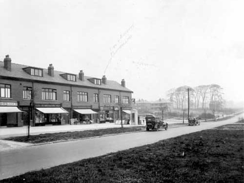 Arow of shops on Easterly Road, looking from the junction with Gipton Wood Road in June 1935. The parade of shops are includes F.A Robson chemists, Beaumonts fruit shop and a bakery on the corner. A Tetley sign hangs above the bakery. An advert on the side of the building advertises Combes ale and stout.