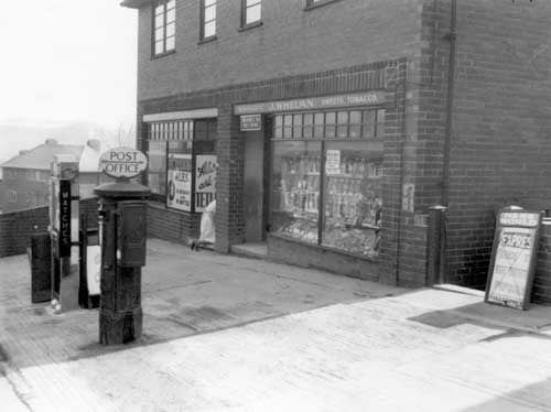 Brander Road Post Office, prop: John Whelan, which is at 72 Brander Road. Next door on the left are the grocery premises of Miss Annie Wilkinson at 74. A cigarette machine and post box can be seen outside. Pictured in April 1939.