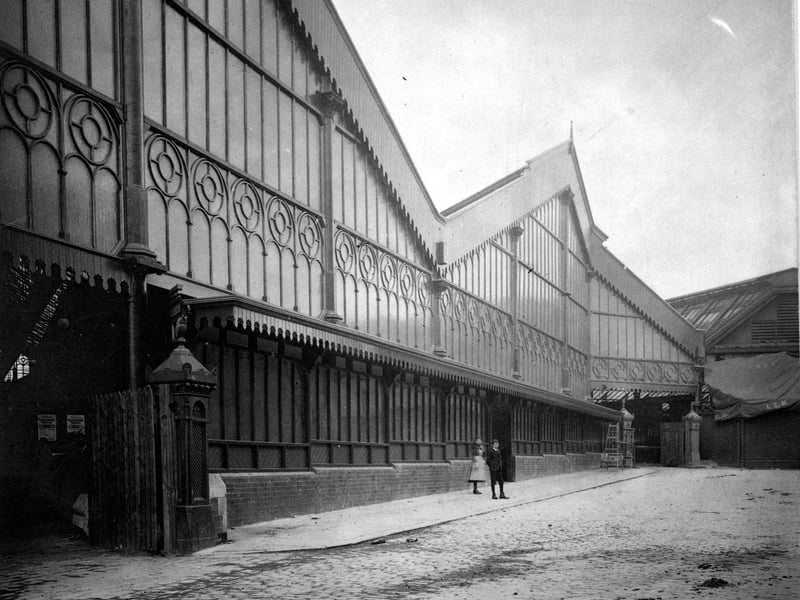 The entrance to Kirkgate market hall on Harper Place (off Harper Street). A boy and girl can be seen standing on pavement between entrances. Pictured in September 1901.