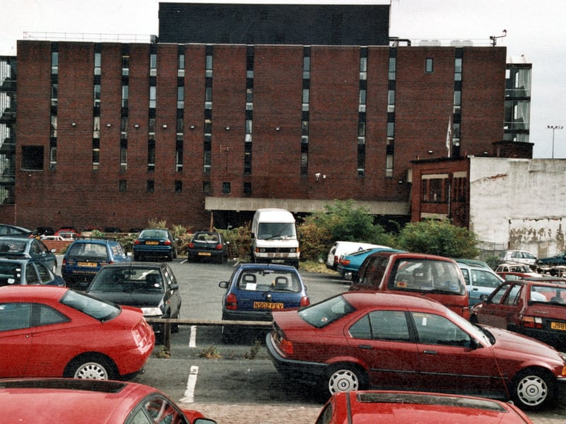 The back of Millgarth Police Station - a six storey building with glass stairwells on either side. To the forefront is the police station's car park. Pictured in September 1999.