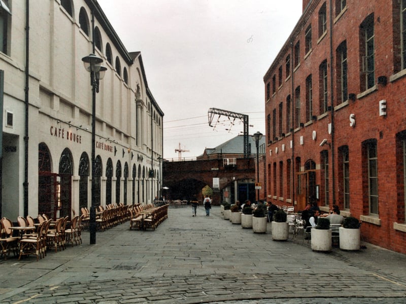 Cafe Rouge and Townhouse bars by the Corn Exchange. People sit round tables outside. A railway bridge and crane are in the background. Pictured in September 1999.