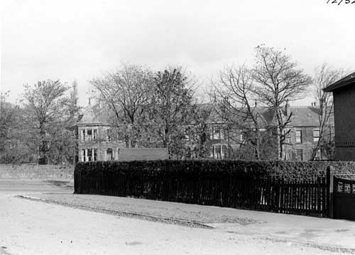 Woodland Park Road, foreground, at the junction with Grove Lane. The house occupying the corner plot, which has a hedge and fencing, is number 46 Grove Lane. The substantial, turreted terraced homes in the background are also in Grove Lane and begin on the left with number 43, following an odd numbered sequence. Pictured in October 1941.