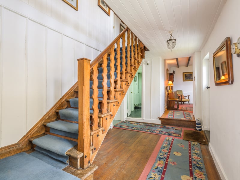 A beautiful, timber staircase with bespoke curved balustrades leads up to the first floor landing.