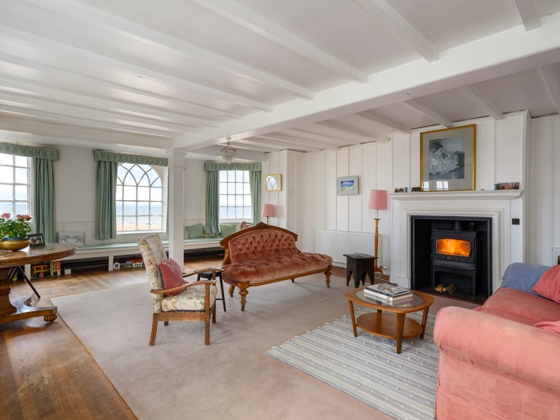 A photo of the sitting room with a wood burning stove and exposed timber beams