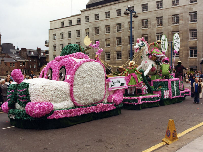 A brightly decorated float by Lewis's department store in association with Trebor. It was one of 70 floats which paraded through the streets of Leeds on the occasion of the 6th Annual Lord Mayor's Parade in June 1979. The procession was over a mile long and included eight marching bands and 400 drum majorettes. 50,000 people turned out to watch. The theme for the parade was 'Together with Children'. Lewis's chose to design this large dog and rocking horse which was cleverly decorated with over 30,000 pink, white and green ribbon bows.