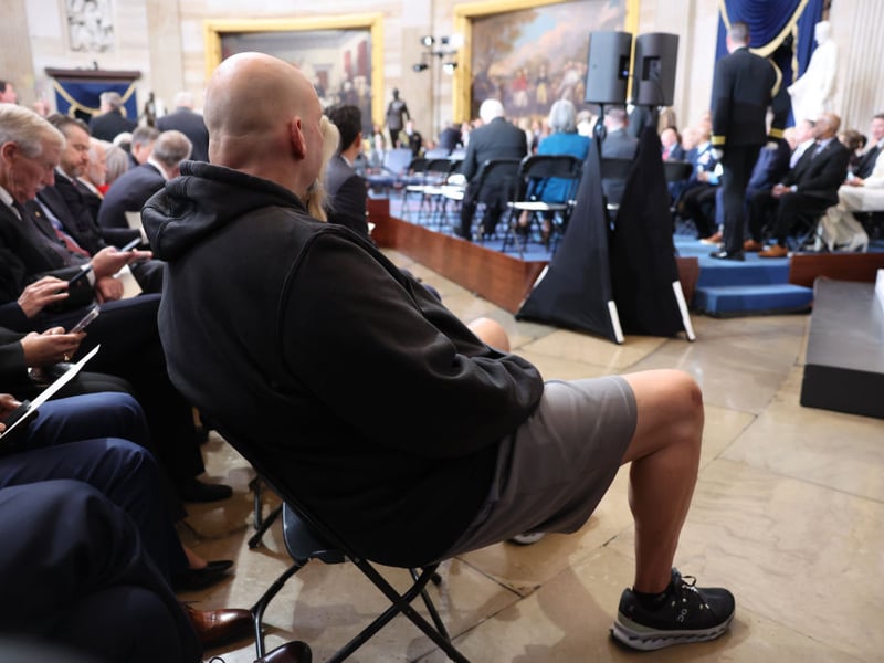 Senator John Fetterman watches the ceremony in shorts and a hoodie.