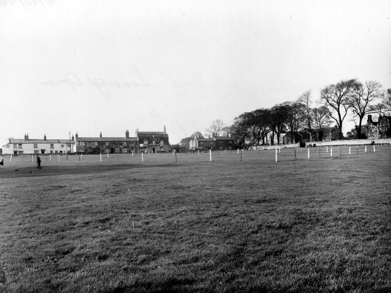 Looking North-West across The Green towards The Cricketer's Arms, which has a sign for John Smith's Magnet Ales on it. Seacroft Grange C.P. School is just visible on the far right. The Green's cricket pitch is roped off. Pictured in October 1954.