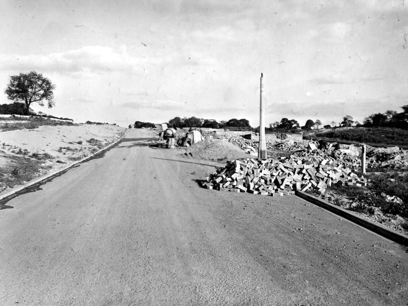 The site of the Seacroft Estate. A half-finished lamp post and a pile of bricks are to the right. Further along the new road is a pile of sand and a cement mixer. Pictured in October 1951.