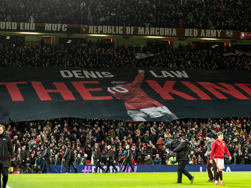 Fans salute Scottish footballing legend Denis Law in the stands.