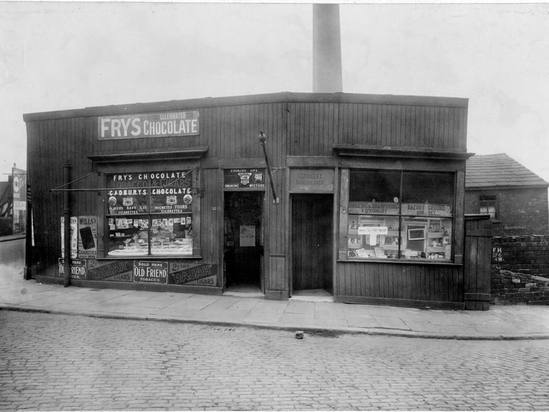 Two retail premises on Botany Bay Place at the junction of Canal Road. The premises on the right is Charles Coakley hairdresser and on the left is Moran Valentine Confectioners. On the front of both shops are retail advertising signs and posters. Pictured in April 1923.