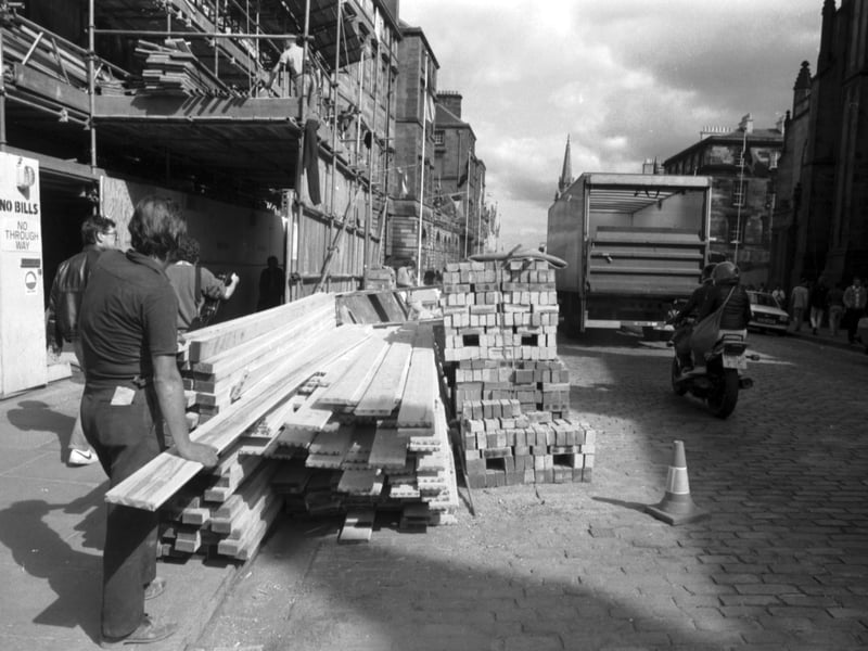 Workmen with planks of wood and a pile of bricks as construction continues in the High Street Edinburgh, August 1985.
