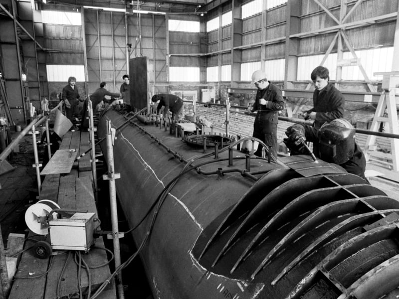 Employees at Henry Robb shipyard, Leith, working on a hull of a submarine in the yard's huge preparation shop, January 1984