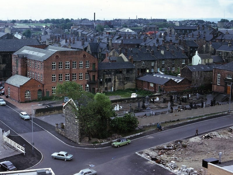 This photo from June 1973 was taken with a telephoto lens from the tower of Morley Town Hall concentrating on the grounds of the Zion Independent Chapel and Wesley Street mill. In this area , besides the demolition of buildings, there has been road re-alignment. Morrisons car park is being extended up to the concrete fence built along the Zion graveyard.