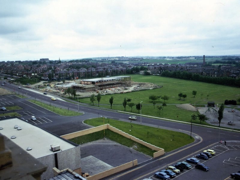 A wide angle view from the Town Hall Tower showing Queensway going across the picture from bottom right to top left. Part of Morrison's car park and shop are shown on the south side of Queensway (no petrol station or car wash yet) whilst on the north there is the children's playground to the right and in the centre the first part (mainly swimming baths) of the Scatcherd Sports Centre being built.