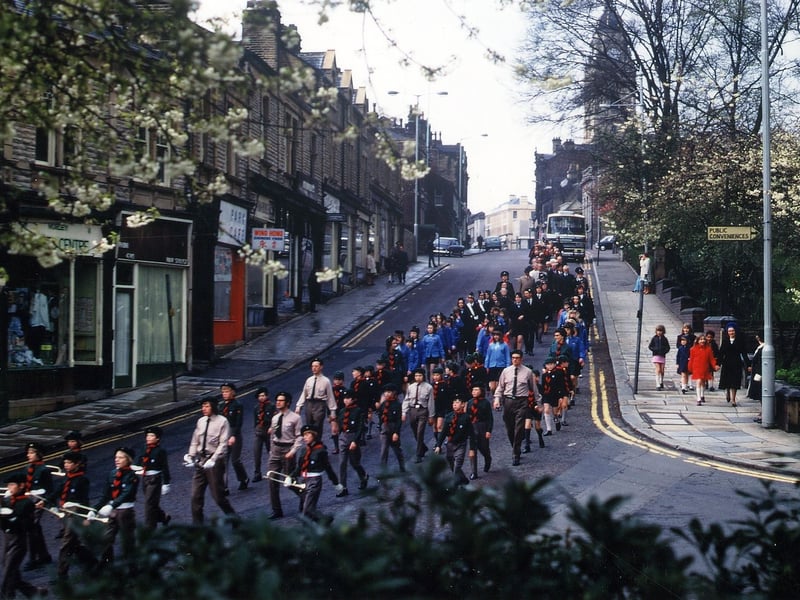 Part of the procession from Morley Town Hall to St. Peter's Parish Church for the last Annual Mayor's Sunday Service of Morley Borough Council. This photograph shows groups of scouts and guides marching down Queen Street. Scatcherd Park and the junction with Queen's Promenade are on the right with the Town Hall seen in the background. Pictured in May 1973.
