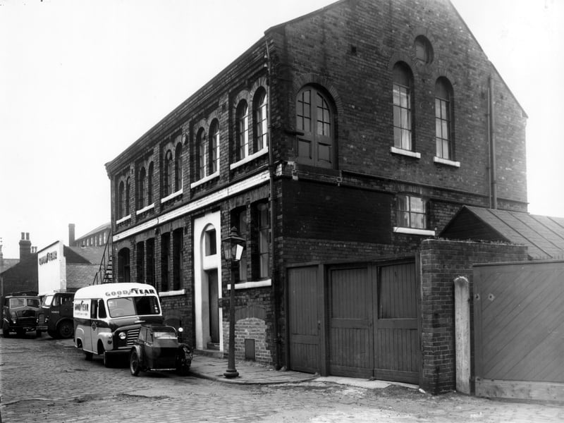 Premises of Goodyear Tyre and Rubber Company, vehicles and a motor-bike parked in the road. Pictured in October 1962.