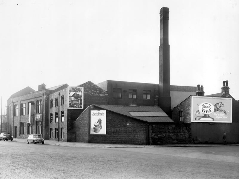 On the left is Sheepscar Street South, moving right the side of property on Vulcan Street can be seen. Large posters advertising Cadbury's chocolate, Esso petrol with the slogan 'Put a Tiger in Your Tank' and McFarlane Lang biscuits. Pictured in October 1962.