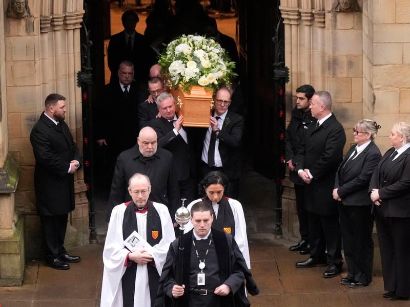 The coffin of Denis Law is carried out of Manchester Cathedral.
