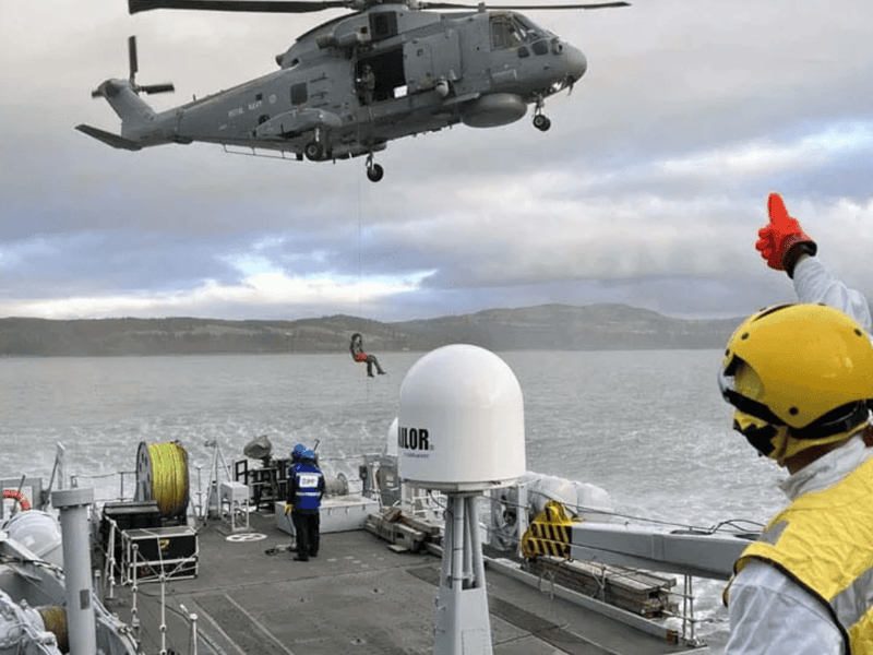 A Merlin helicopter from RNAS Culdrose practises winching a sailor from Cattistock's upper deck.