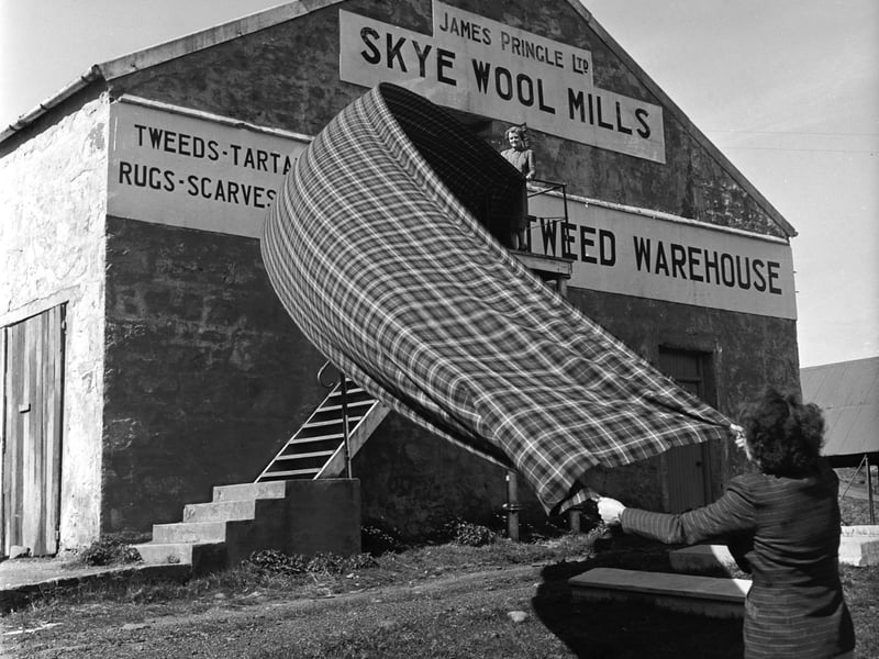 Two women airing a stretch of tartan outside James Pringle Ltd's Skye Wool Mill on the Isle of Skye in 1955.