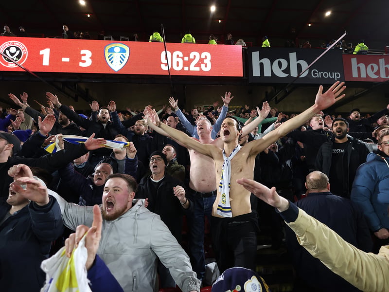 Leeds fans celebrate a famous comeback with the Bramall Lane scoreboard behind them