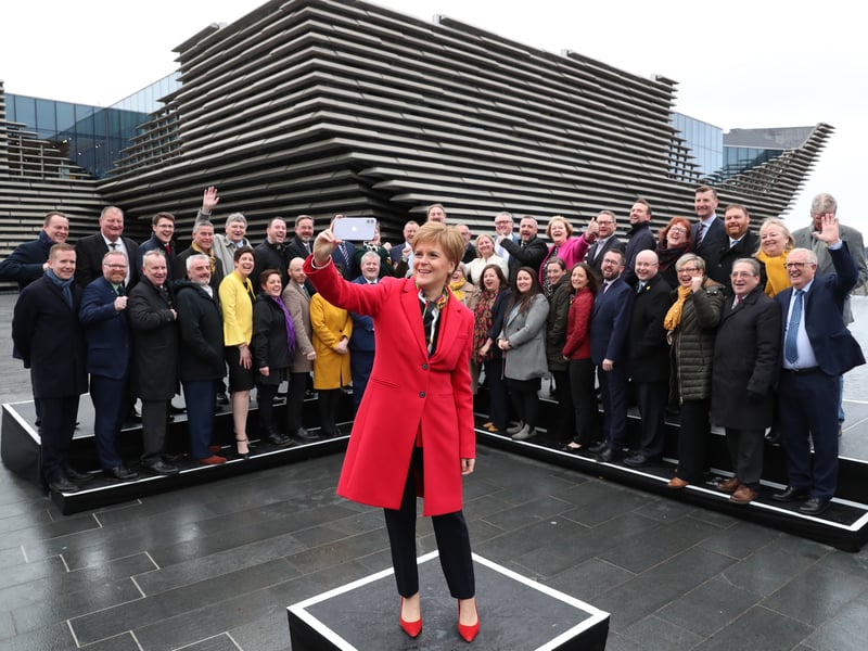 First Minister Nicola Sturgeon takes a selfie as she joins SNP's newly elected MPs for a group photo call outside the V&A Museum in Dundee.