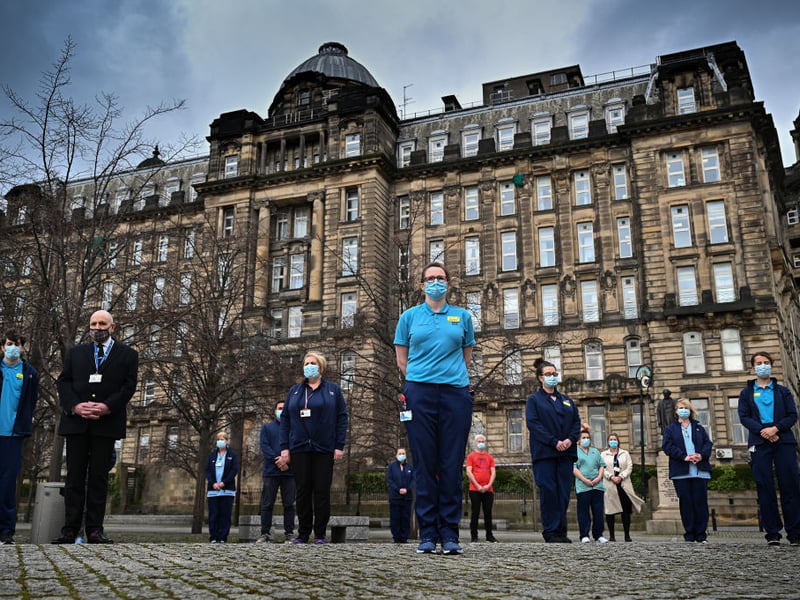 Staff from the Glasgow Royal Infirmary gather outside the hospital for a minute's silence on March 23, 2021 in Glasgow, Scotland. Marie Curie Cancer Charity had organised a National Day of Reflection on the first anniversary of the day Britain entered Coronavirus lockdown.