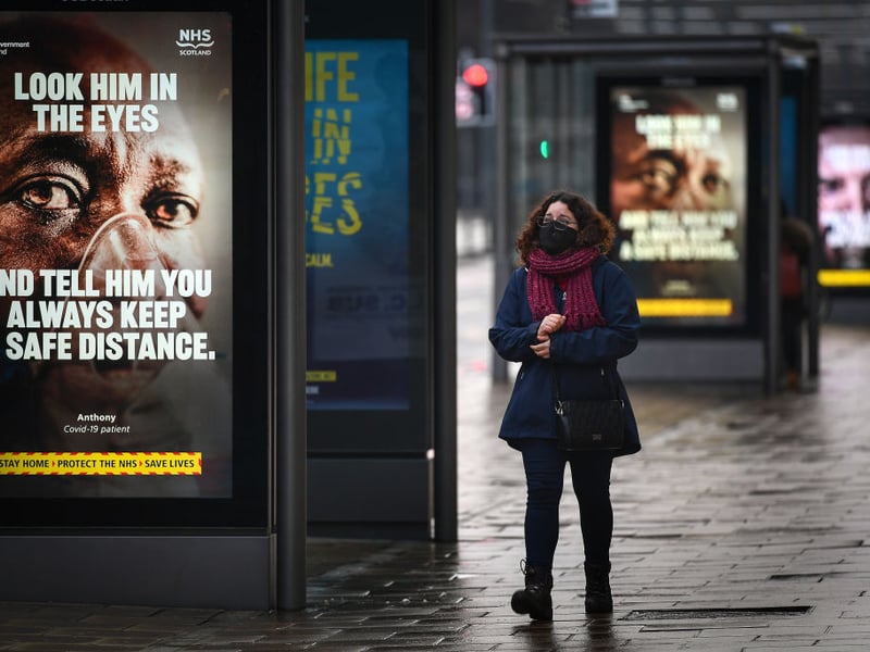 A member of the public walks past a government poster reminding people to socially distance and abide by the lockdown restrictions on Edinburgh's Princes Street