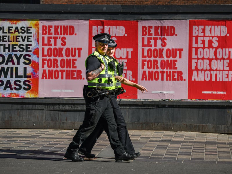 Two police officers walk past posters on Sauchiehall Street during the coronavirus lockdown.