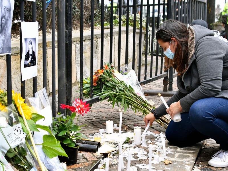 A fan lights a candle outside of the hotel where Foo Fighters' drummer Taylor Hawkins died, on March 26, 2022 in Bogotá. - Foo Fighters' drummer Taylor Hawkins, 50, of the multi-Grammy award-winning rock group the Foo Fighters has died while on tour in Bogota, Colombia, his bandmates said in a statement on March 25, 2022