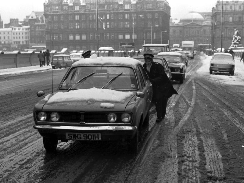 A kind traffic warden pushes a car on North Bridge during the blizzards in Edinburgh, January 1978.
