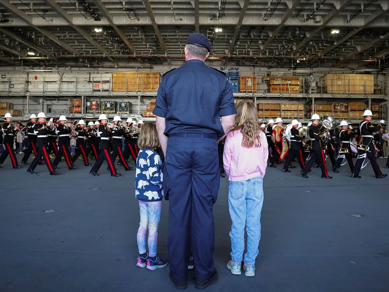 HMS Prince of Wales welcoming families and affiliates on board ahead of Indo-Pacific deployment. Pictured: The flagship's Commanding Officer, Captain Will Blackett, with his children watching the Royal Marines Band Service.