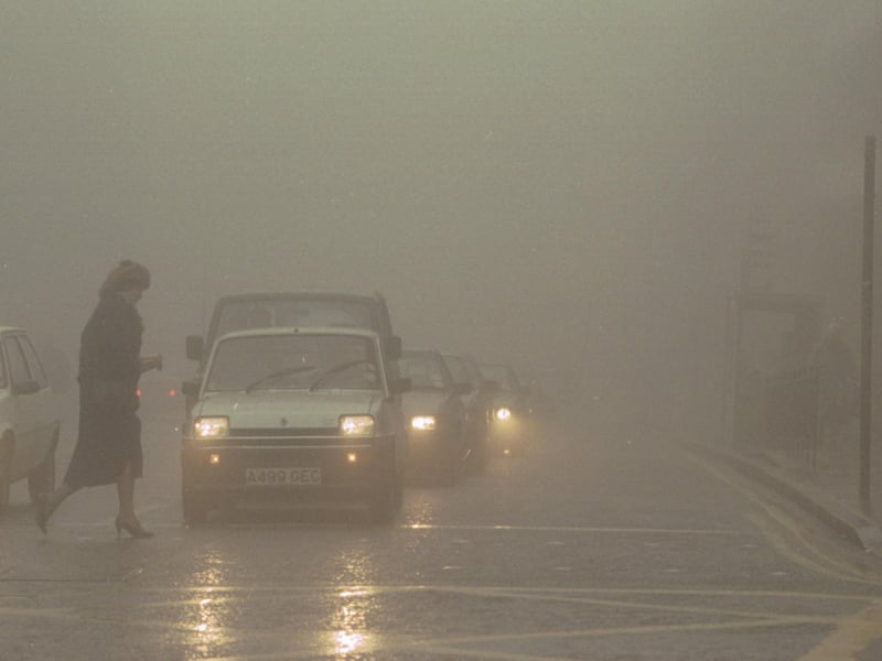 A woman crosses the street as a heavy fog descends on North Bridge in Edinburgh in March 1991