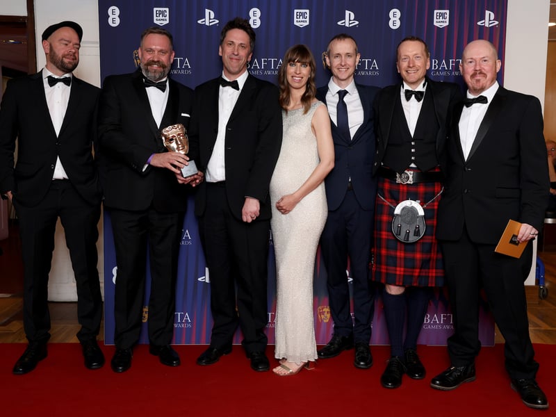John McCormack, Ed Daley, Laura Dodds, Rob McCoughlin, Frasier Colley, Dan Pinchbeck and Louis Larsson-De Wet pose in the winners room with the New Intellectual Property Award on behalf of the Development Team for 'Still Wakes the Deep' during the BAFTA Games Awards 2025.