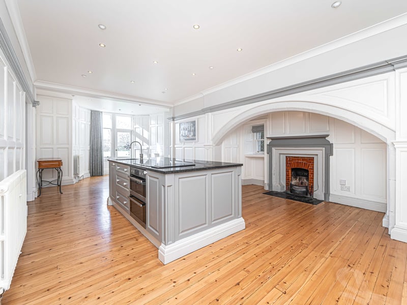 The expansive kitchen features a central island unit that includes a sink and cooker
