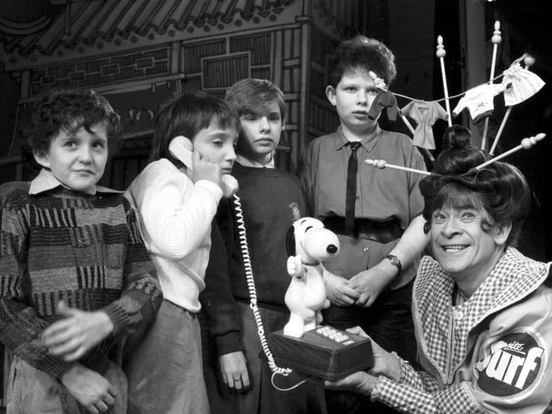 Scottish entertainer Stanley Baxter, playing Widow Twankey in Aladdin at the King's theatre, presents a Snoopy telephone to four children from Graysmill school in Edinburgh, December 1985.