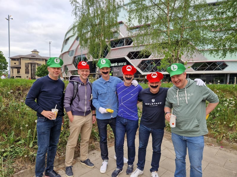 A group of Marios and Luigis finish their McDonald's before the darts.