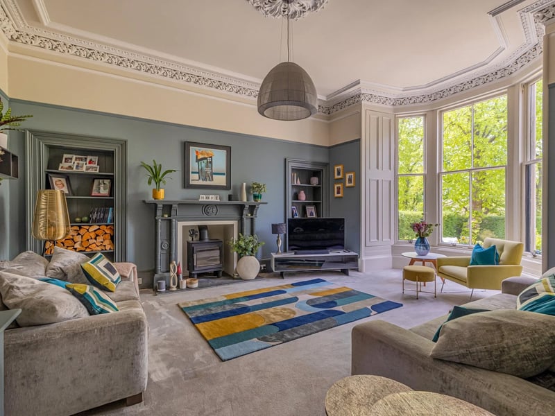 The living room has traditional cornicing and a large bay window as well as a wood burning stove.