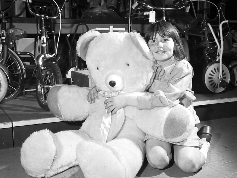 A little girl with a giant teddy bear in the toy department of Jenners' store, Edinburgh in December 1977.